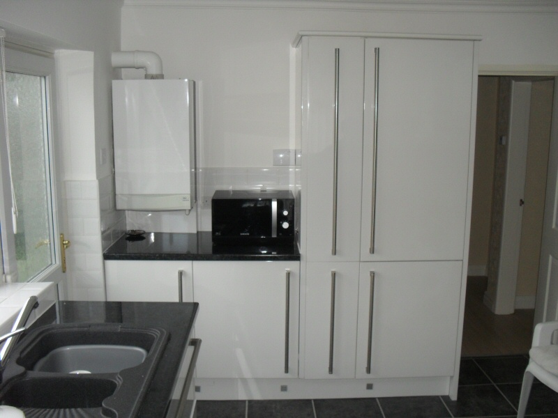 Photo - High Gloss Kitchen (2 of 2) - View of large kitchen cupboard storage with integrated fridge and freezer. - Fitted Kitchens and Bathrooms - Home - © J C Joinery